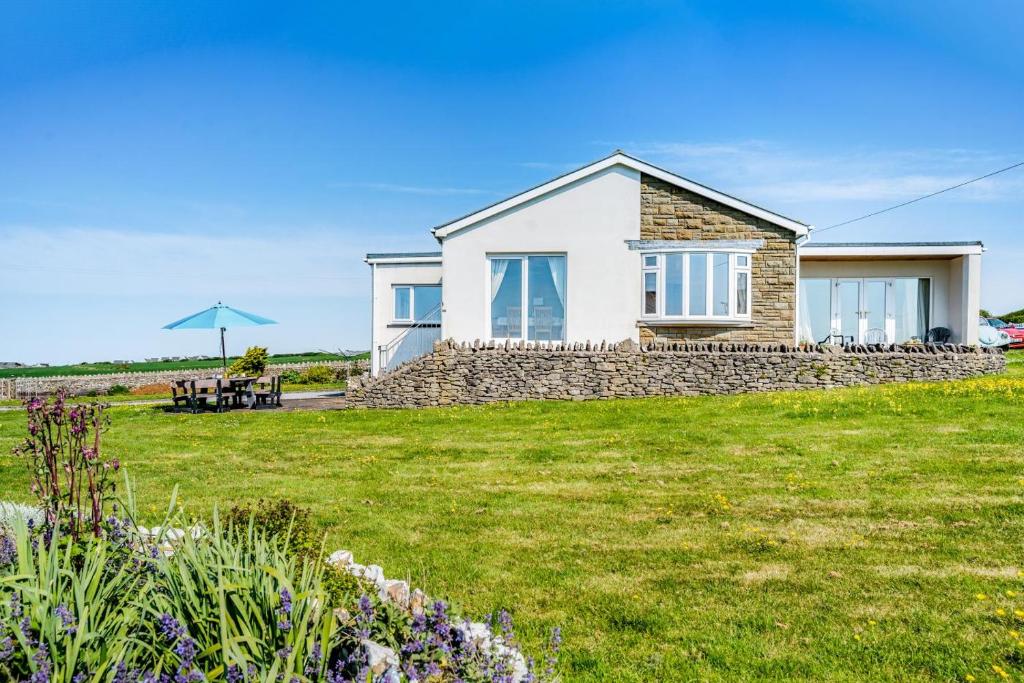 a house on a grassy field with a windmill at Heavenly View in Southerndown