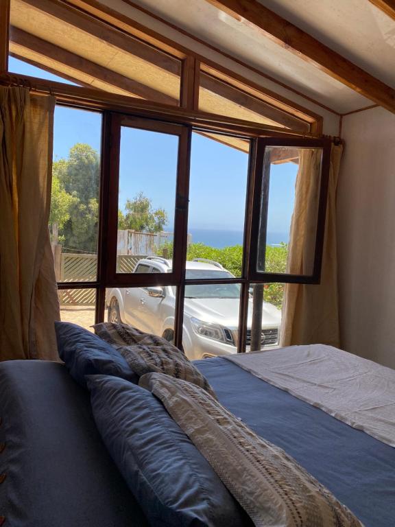 a bed in a room with a large window at Malibu Hostal Boutique in Maitencillo