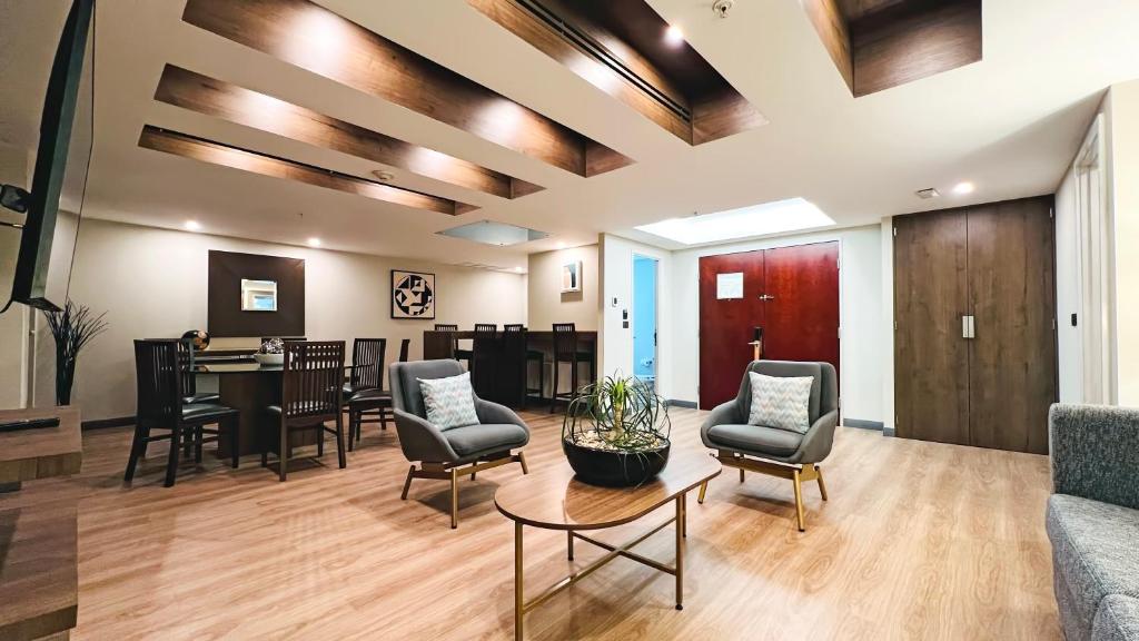 A hotel lounge with armchairs, a coffee table and a small dining area.