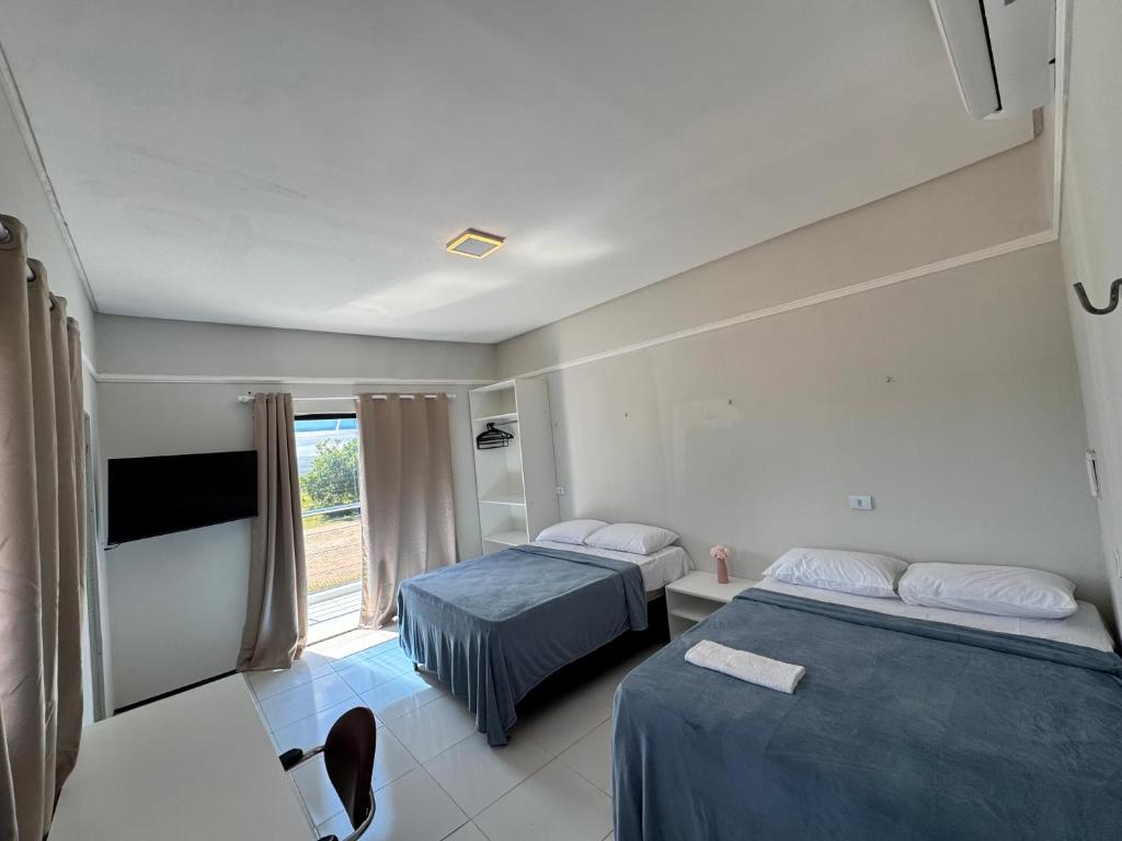 a hotel room with two beds and a window at Pousada do Horto in Juazeiro do Norte