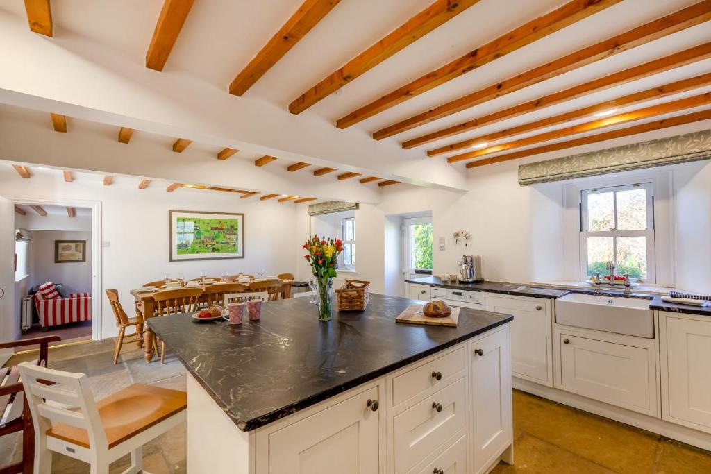 - une cuisine avec des placards blancs et une table fleurie dans l'établissement Southwaite Cottage, à Outhgill