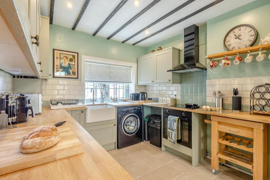 une cuisine avec des murs verts et une horloge au mur dans l'établissement The Olde Cottage - Hythe, à Hythe