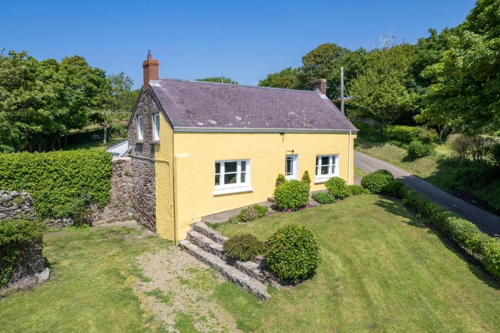 a yellow house with a garden in front of it at Hoopers Cottage in Saint Brides