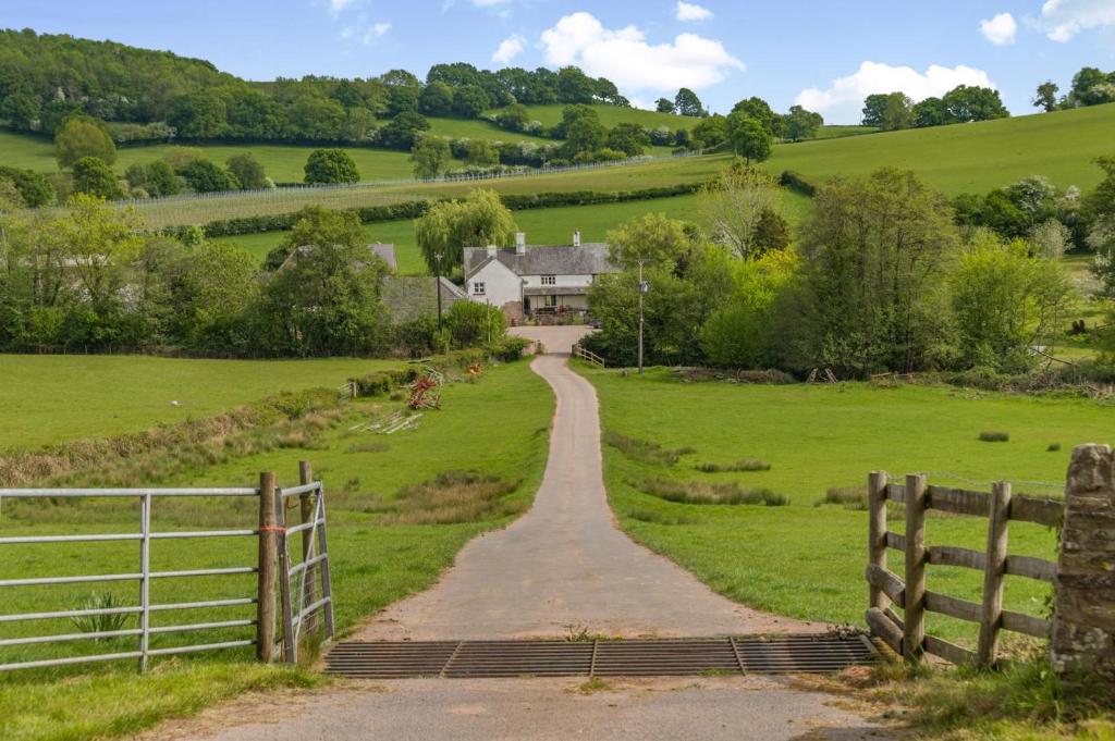 un camino de tierra en un campo con una casa en Great Tre-Rhew Farm, en Llanvetherine