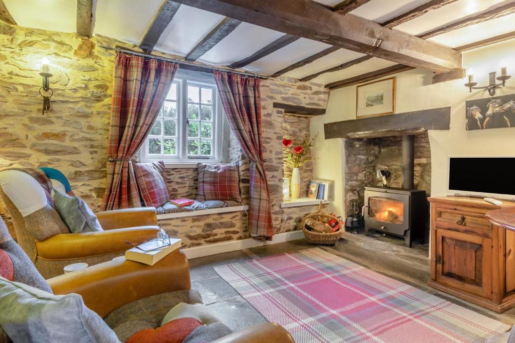 a living room with a fireplace and a tv at Lane Cottage in Dulverton
