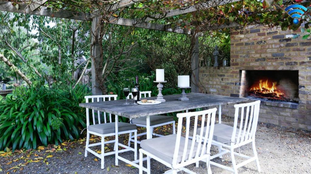 una mesa y sillas con chimenea en un patio en Poppy Cottage, en Exeter