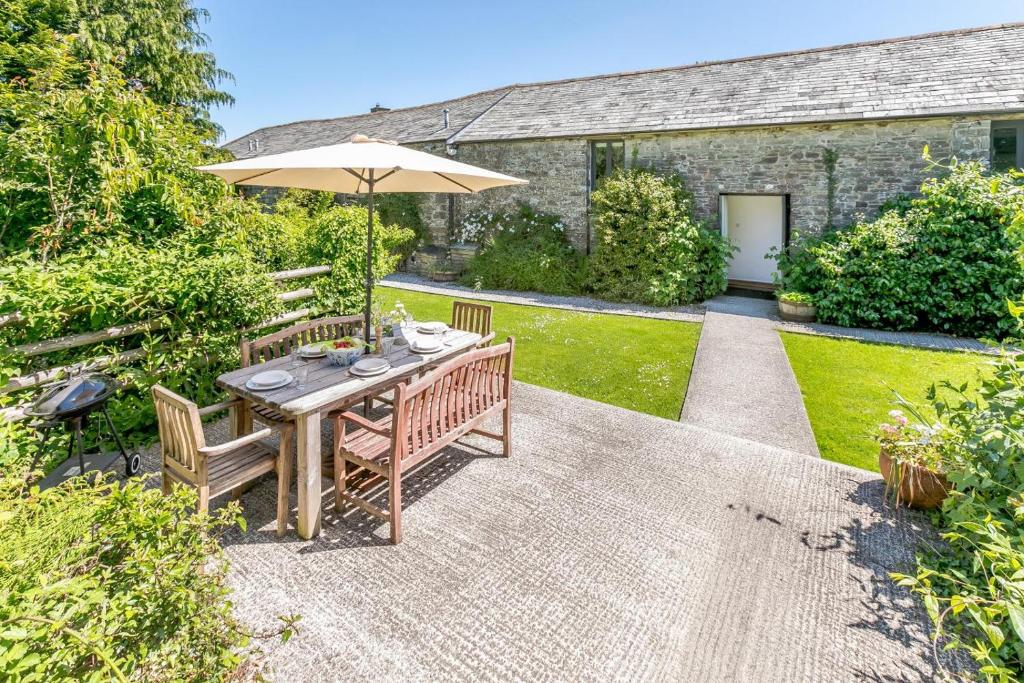 a patio with a table and an umbrella at The Lambs Barn in Lewannick