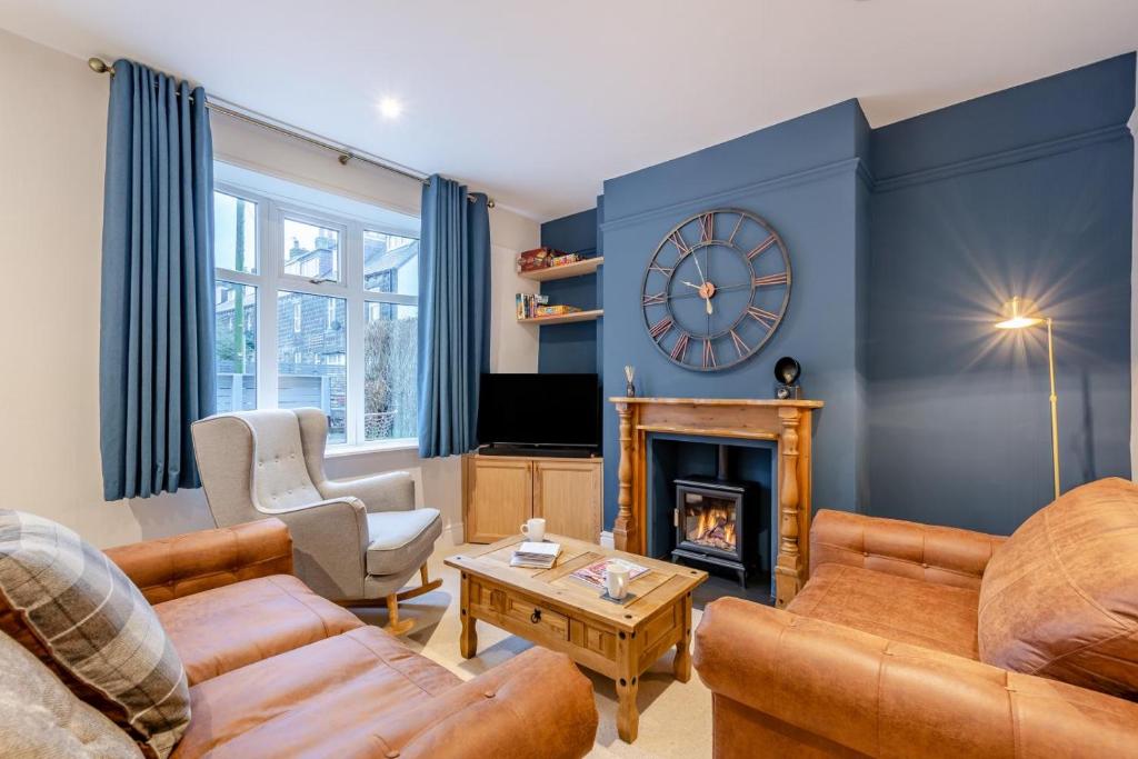 伊尔克利Ilkley Moor View Cottage的客厅设有壁炉和墙上的时钟
