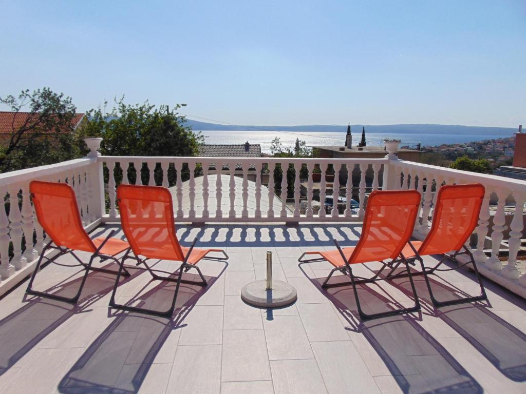 4 chaises orange et une table sur un balcon dans l'établissement Apartement Marija, à Novi Vinodolski