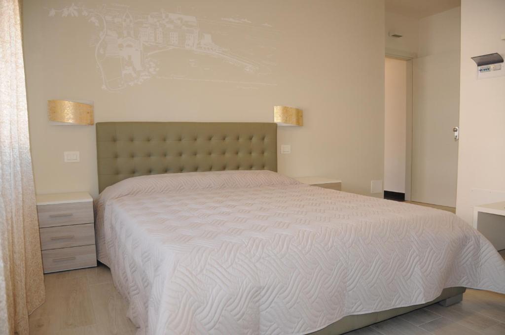 um quarto com uma cama grande e uma colcha branca em Affittacamere La Perla em La Spezia