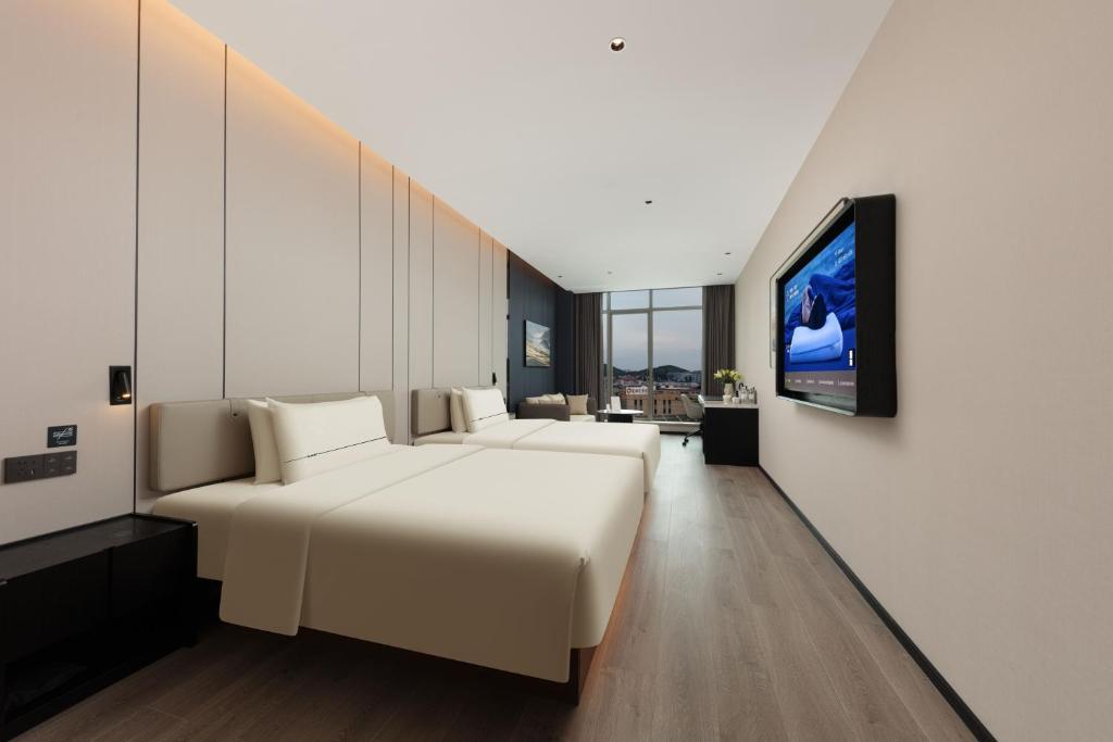 Atour Hotel Changsha Yuelu Mountain Orange Isle في تشانغشا: غرفة نوم بسرير ابيض كبير وتلفزيون