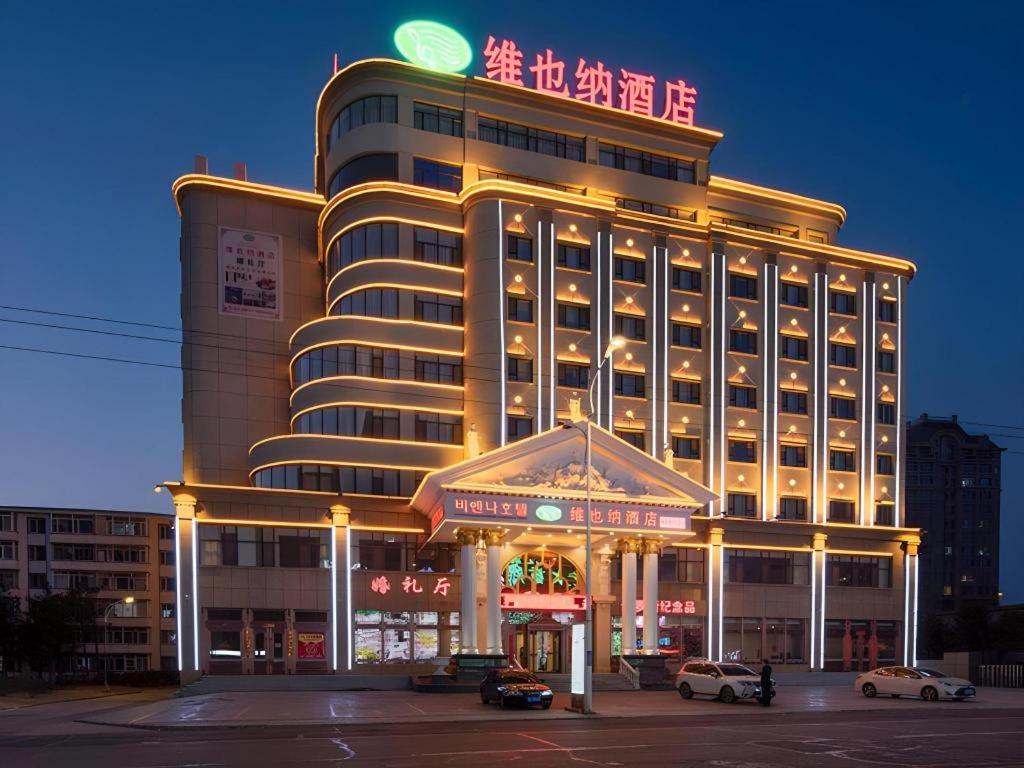 a large building with a restaurant in front of it at Vienna Hotel Hunchun East Market Government Affairs Center in Hunchun