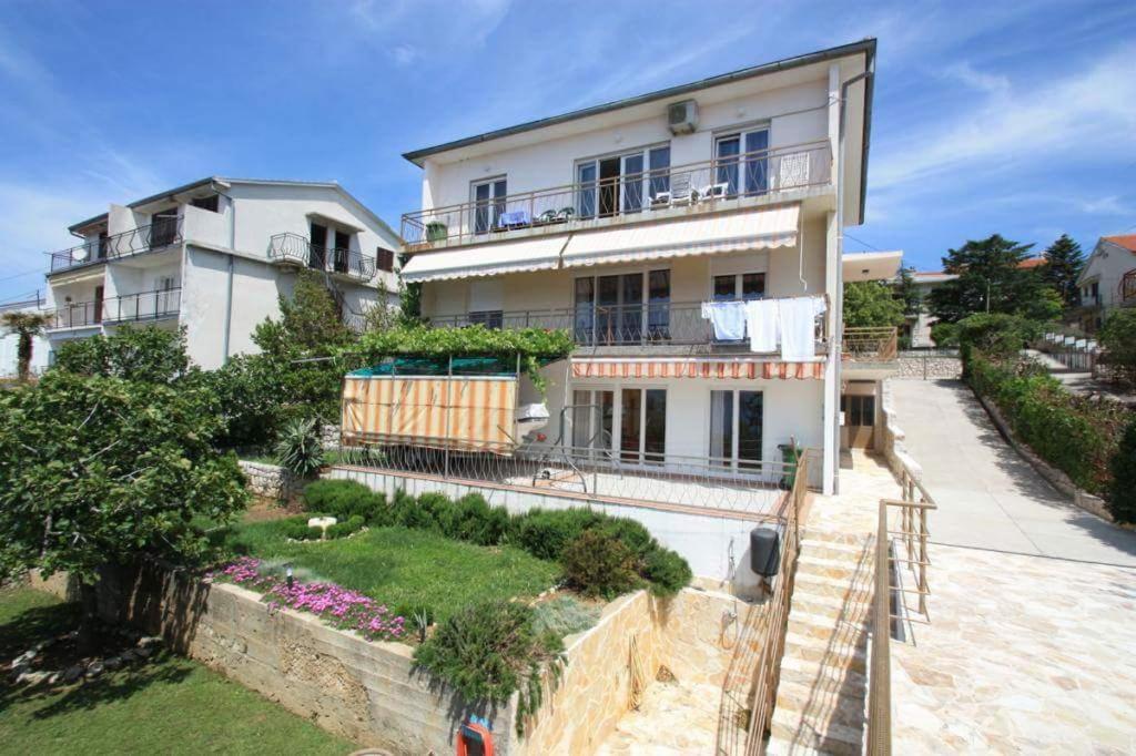 a large white house with a garden in front of it at Apartman Pako i Ivano in Novi Vinodolski