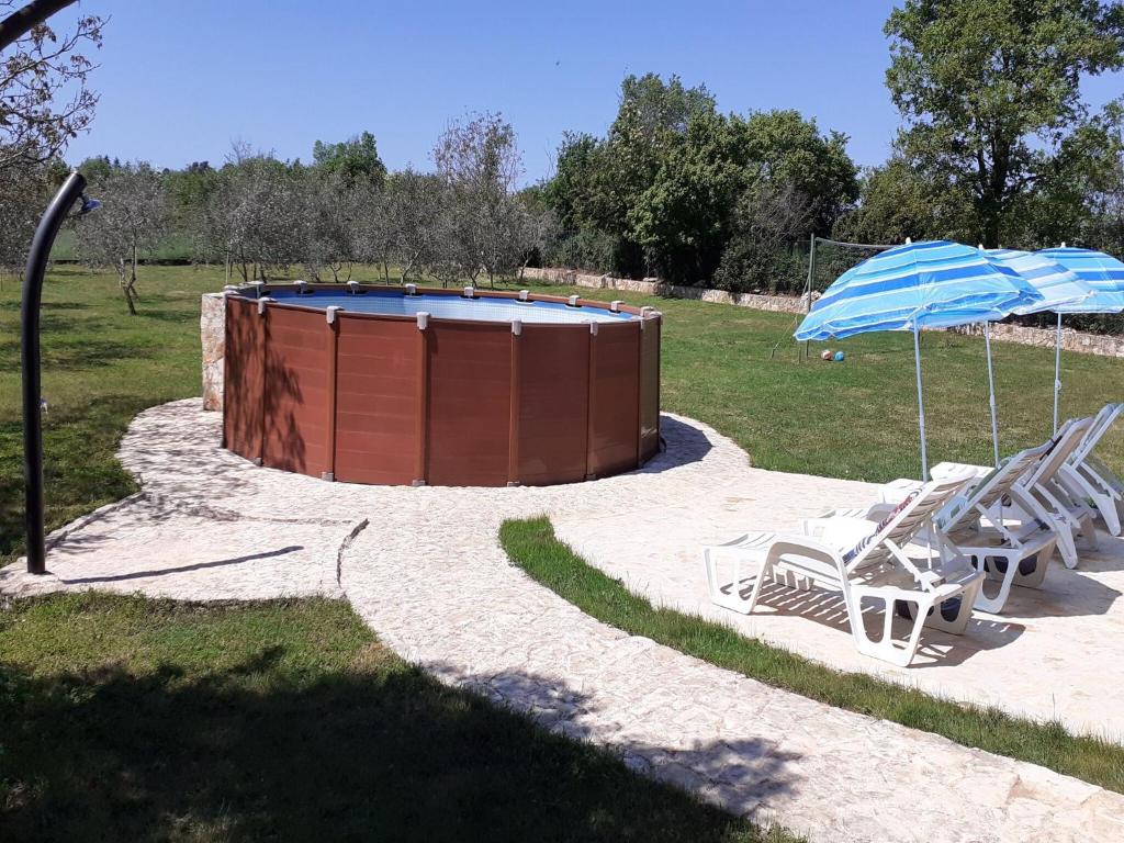 a couple of chairs and an umbrella next to a pool at Charming Pool Home Near Pula in Pula