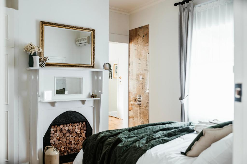 a bedroom with a fireplace with a mirror and a bed at Historic Benambra Boutique Accommodation Queenscliff c1883 in Queenscliff