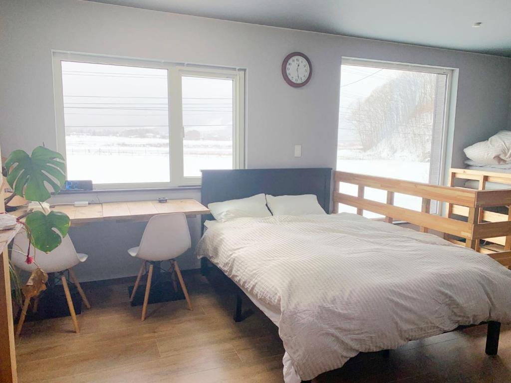 a bedroom with a bed and a desk and two windows at Svalbard Residence - Vacation STAY 18446 in Minamifurano