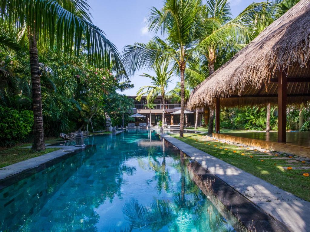 a swimming pool in front of a resort with palm trees at Villa Yoga in Seminyak