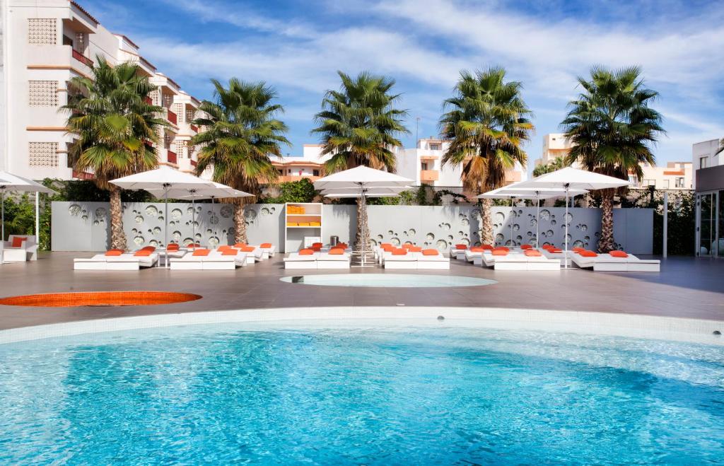 ein Pool in einem Hotel mit Sonnenschirmen und Stühlen in der Unterkunft Ibiza Sun Apartments in Playa d'en Bossa