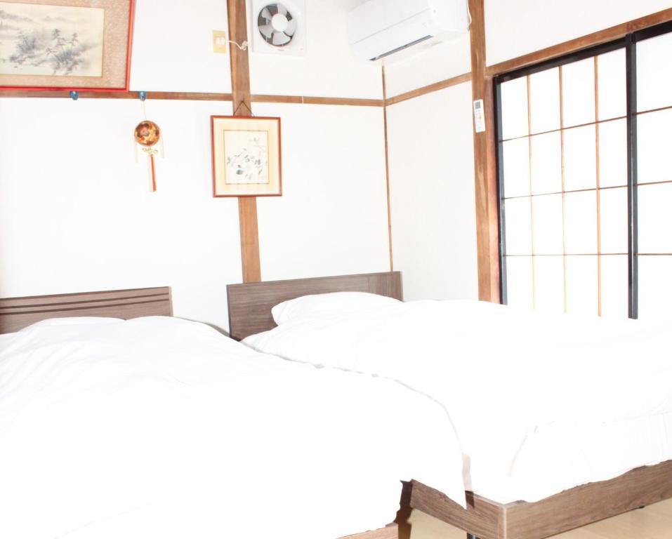 a bedroom with two beds and a clock on the wall at Oyado Sakura - Vacation STAY 88440v in Matsumoto