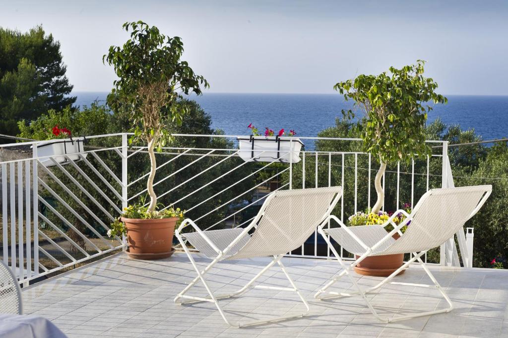 two white chairs and potted plants on a balcony at Case Della Baia in Castellammare del Golfo