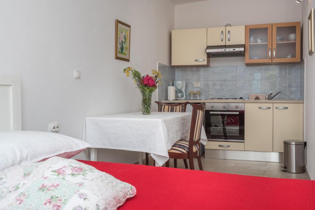 a kitchen with a table with a vase of flowers at Apartments Coce in Trogir