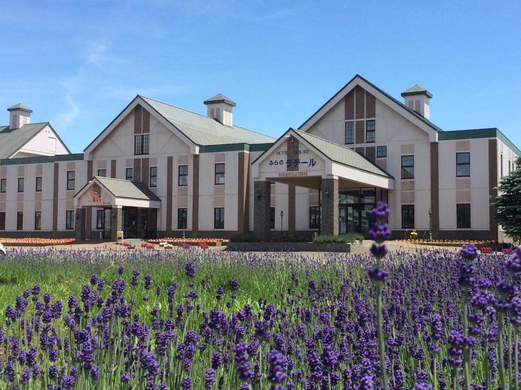 中富良野町的住宿－富良野拉漁村酒店，一座在前面布满紫色花的建筑