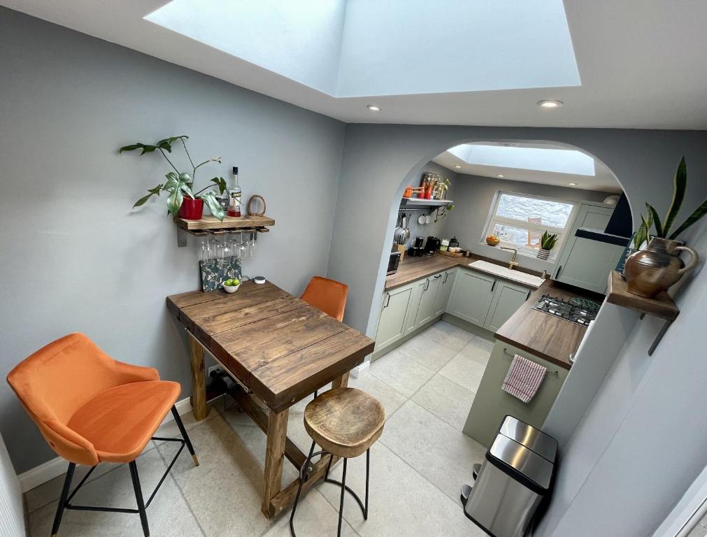 a small kitchen with a wooden table and orange chairs at Globe Cottage in Glastonbury