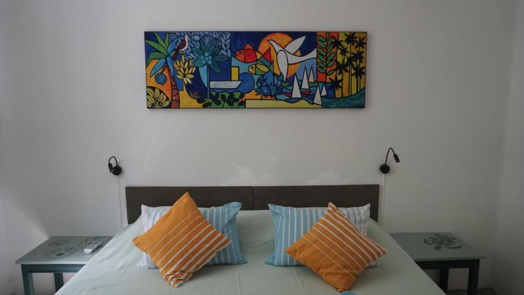 a bed with orange and blue pillows and a painting at Gardens Retreat, Peaceful Bungalow near Beach in Pereybere