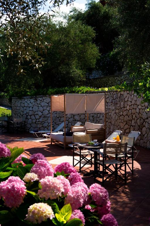 a garden with chairs and a table and flowers at Evridiki's Villas in Agios Nikitas