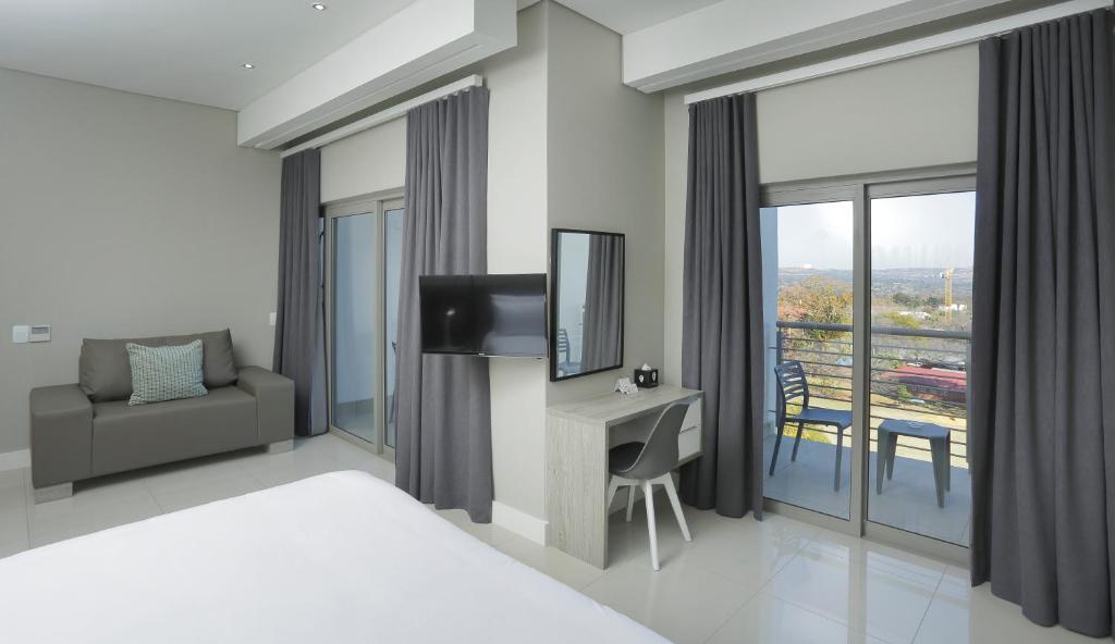 a bedroom with a bed and a desk with a television at The Capital on Bath in Johannesburg