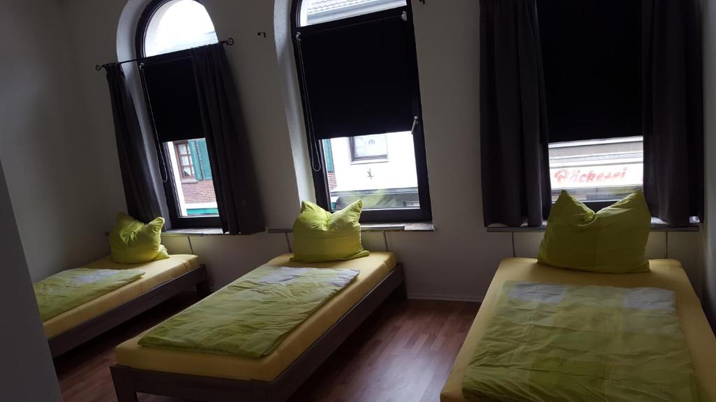 2 Betten mit gelben Kissen in einem Zimmer mit Fenstern in der Unterkunft Boardinghaus Niederrhein in Viersen