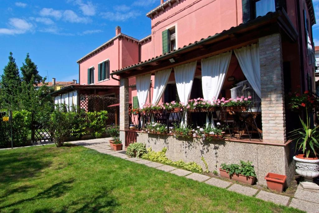 ein rosa Haus mit Blumen im Hof in der Unterkunft B&B 500 in Lido di Venezia