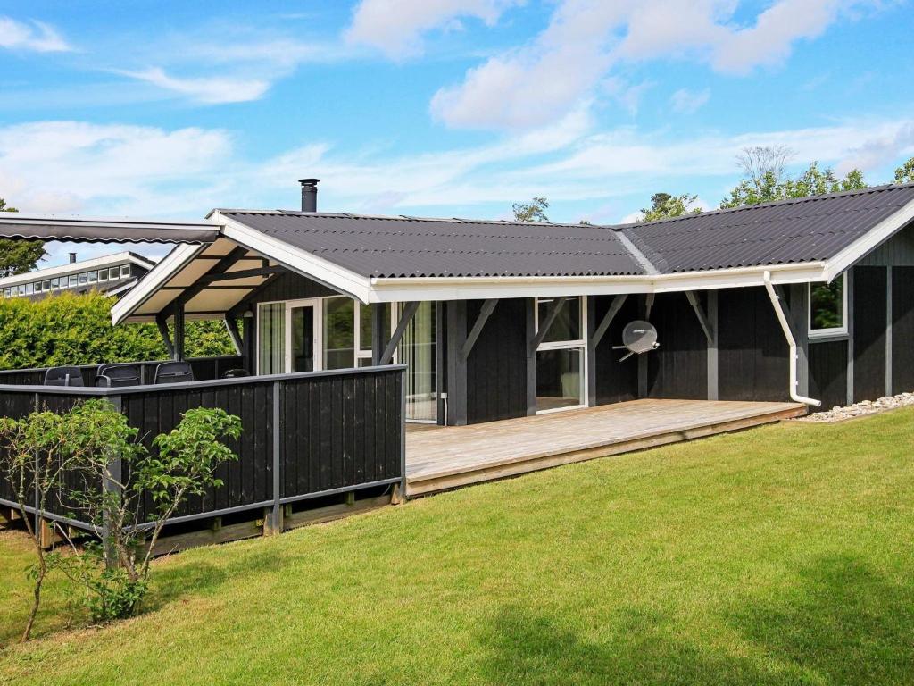 a house with a black roof and a wooden deck at 4 star holiday home in Hals in Hals