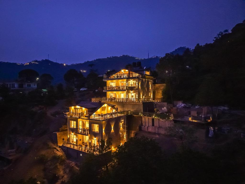 a large building with lights on it at night at Konifer Greyvine in Kasauli