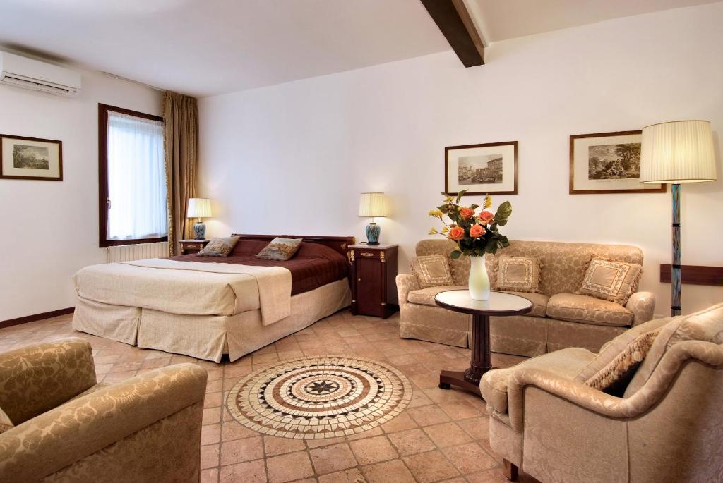a bedroom with a bed and a couch and chairs at Villa Dacri in Venice-Lido