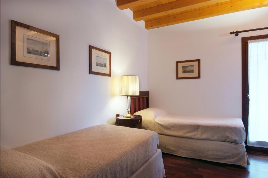 a bedroom with two beds and a lamp and a window at Villa Dacri in Venice-Lido