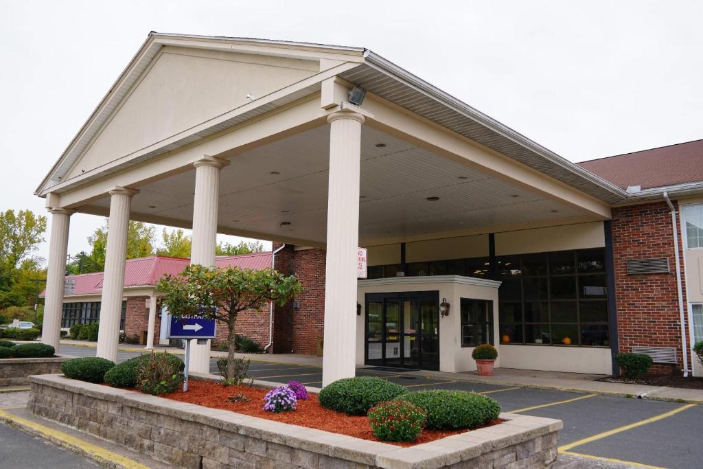 a building with columns and flowers in front of it at Rodeway Inn & Suites East Windsor in East Windsor