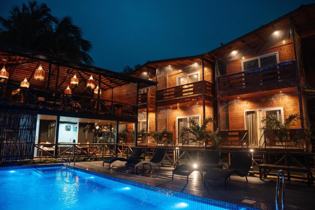 a villa with a swimming pool at night at Tranquillo By The Beach, Candolim in Candolim