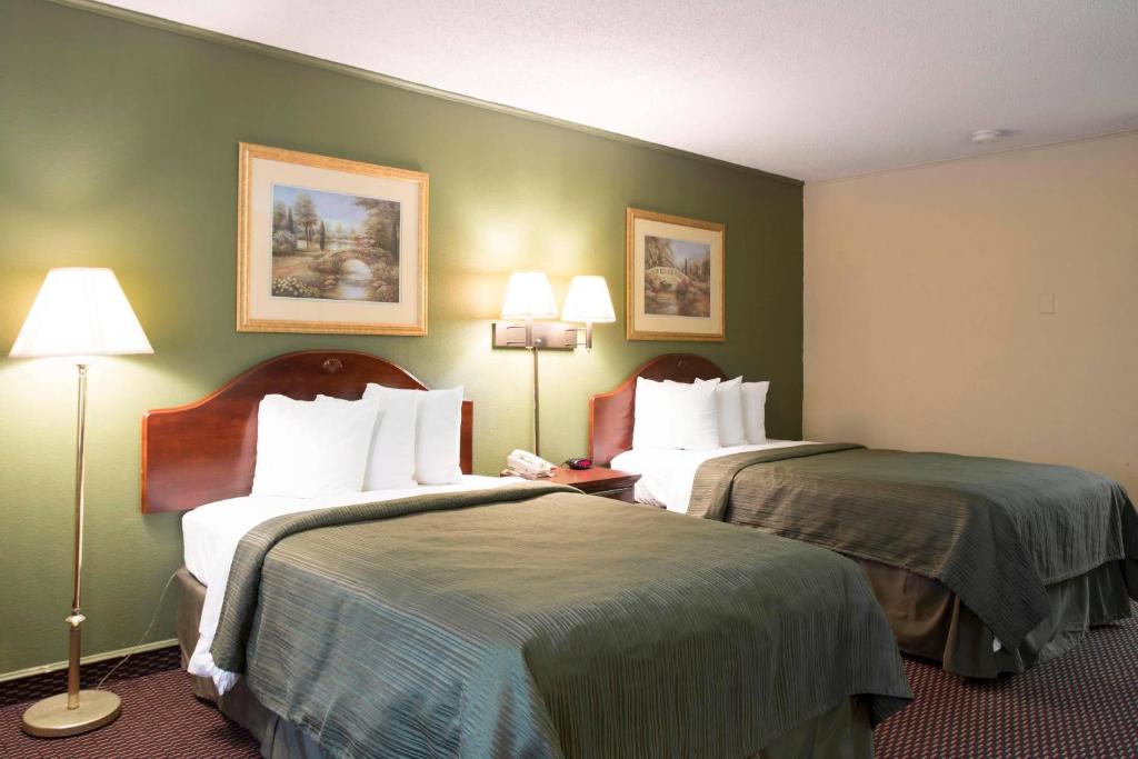 two beds in a hotel room with green walls at Rodeway Inn Harbison Area in Columbia