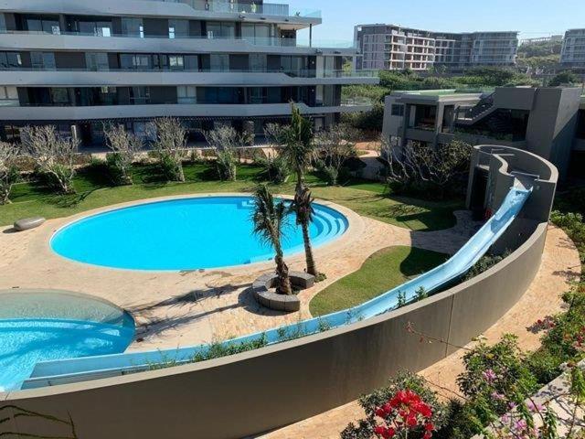 a large swimming pool next to a large building at Pebble Beach 204 in Sibaya