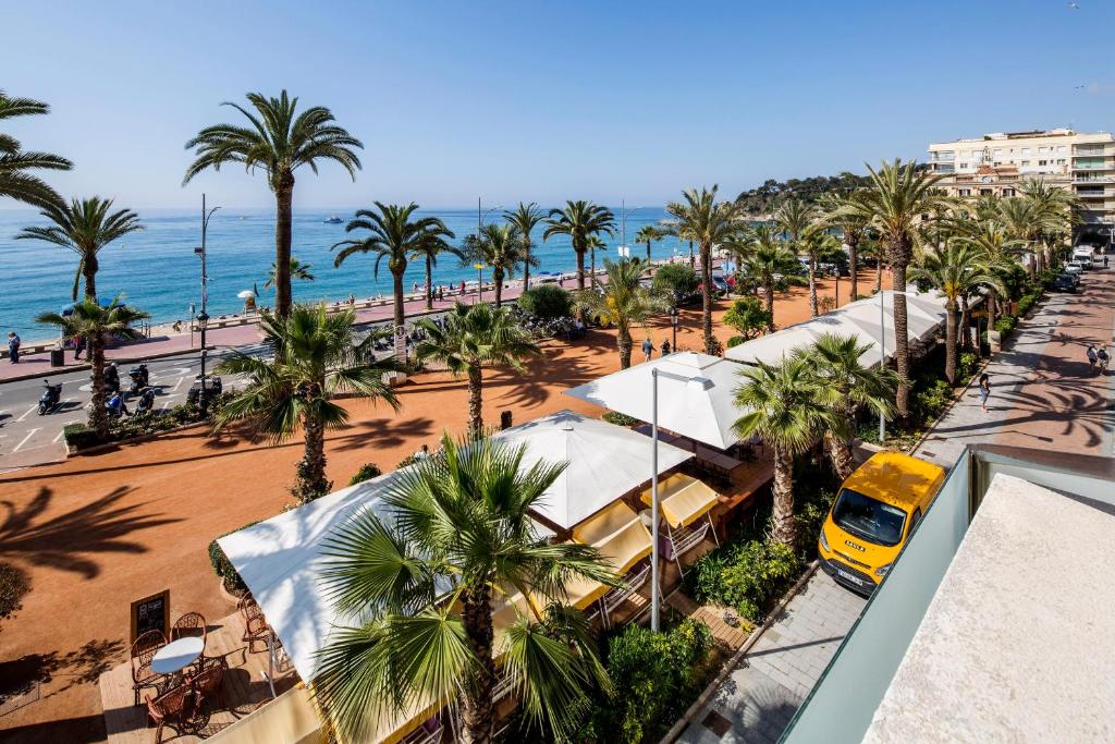 an aerial view of a beach with palm trees and a yellow van at URH Excelsior in Lloret de Mar