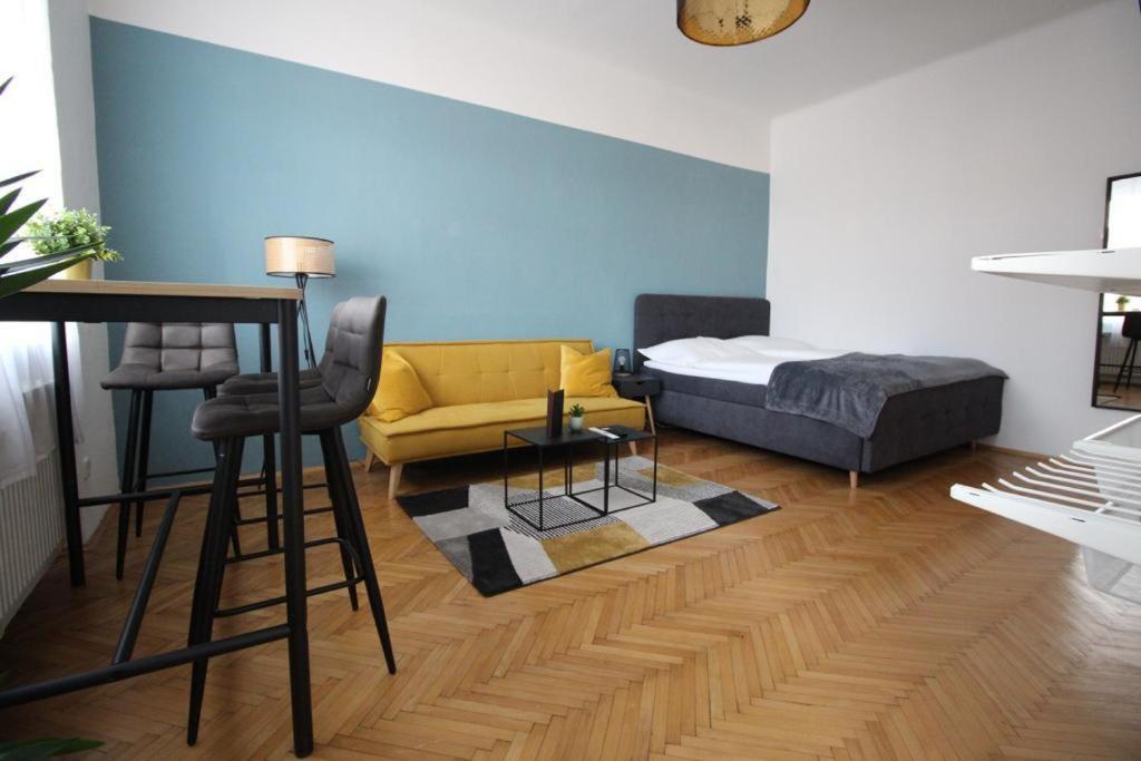 - un salon avec un lit et un canapé jaune dans l'établissement Moderne & zentrale Citywohnung nahe Stadthalle, Messe & Sportpark, à Graz