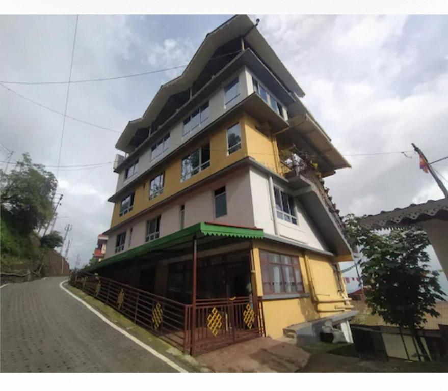un edificio amarillo y blanco al lado de una calle en Aura Homes, en Gangtok