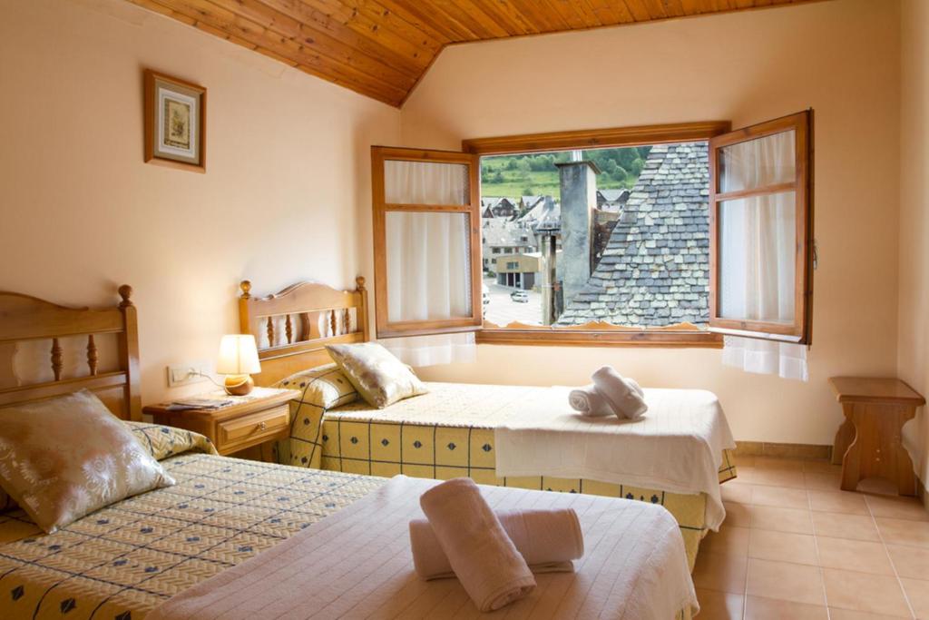 1 dormitorio con 2 camas y ventana en Hostal Aiguamog, en Salardú