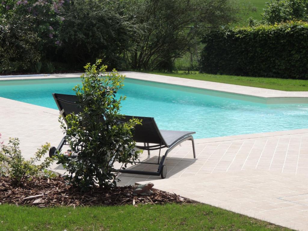 a black bench next to a swimming pool at chambres d'hôtes le Boyer in Mantenay-Montlin