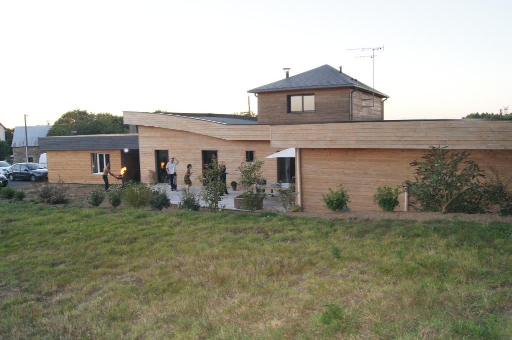 une maison avec des personnes debout devant elle dans l'établissement Maison en ossature bois, à Plaintel