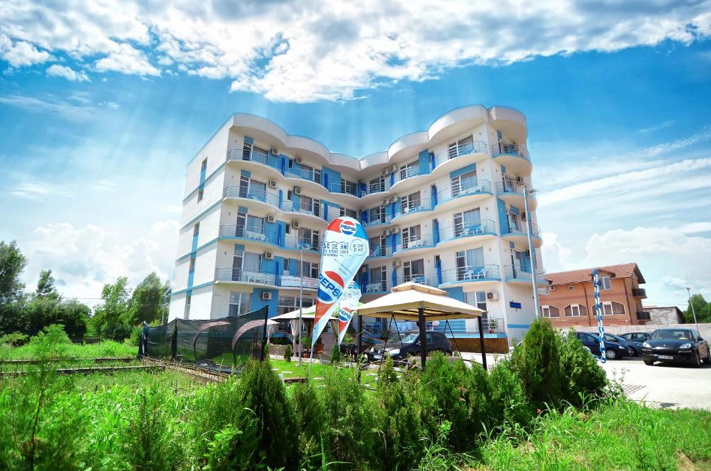 a large white building with an umbrella in front of it at Babylonia Resort in Costinesti