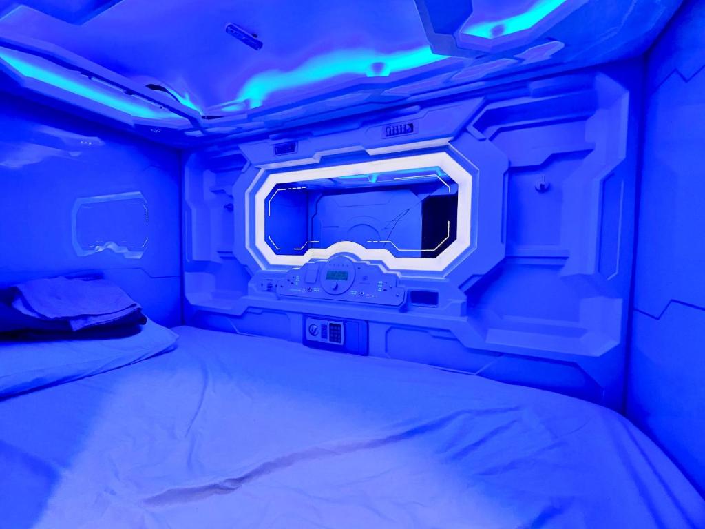 a room with a bed with a tv and blue lights at My Capsule Hotel in Johor Bahru
