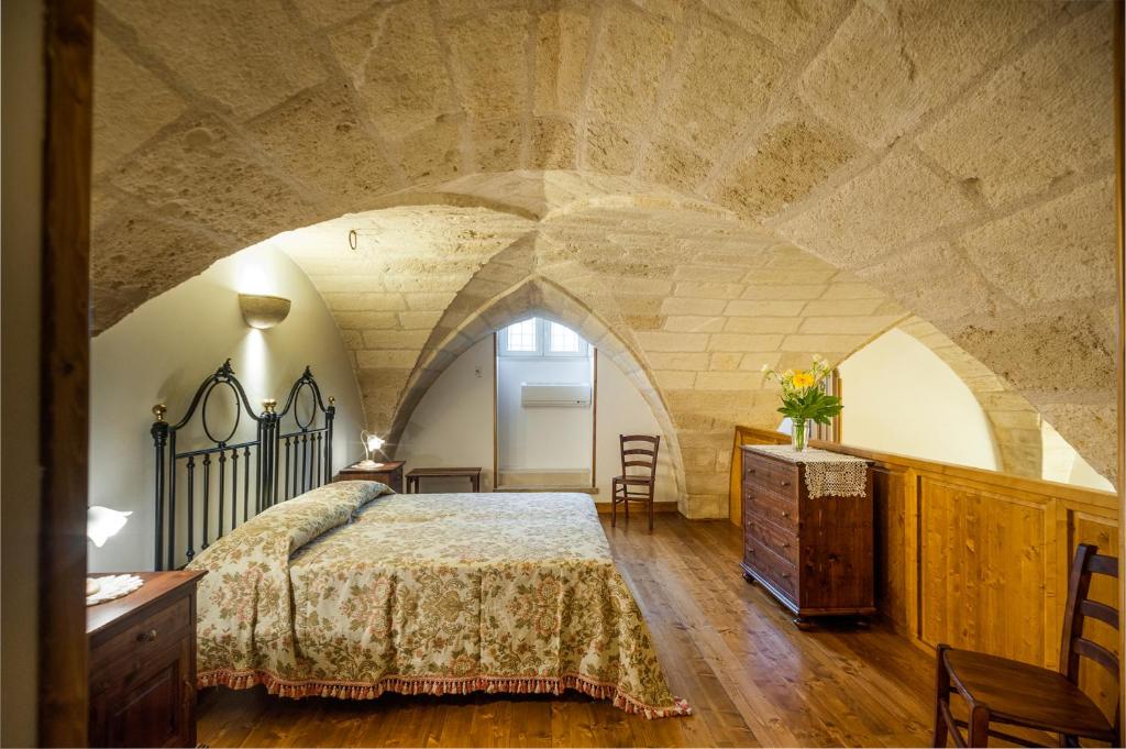 - une chambre avec un grand lit et un mur en pierre dans l'établissement Tre Volte Belle, à Carpignano Salentino