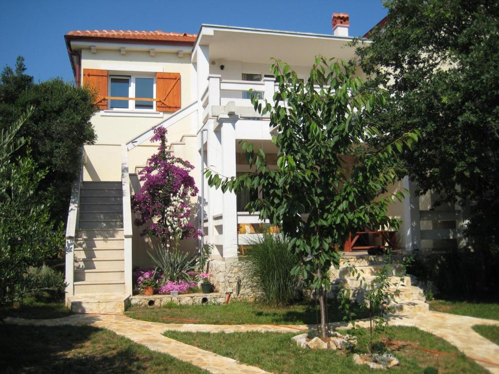 a white house with flowers in the yard at Apartment Vanilla in Borovići